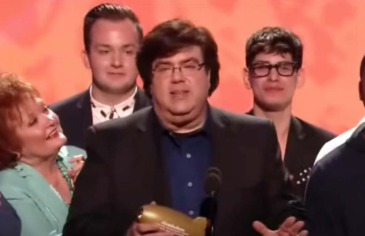 Dan Schneider is surrounded by Nickelodeon stars as he receives the Lifetime Achievement Award at the 2014 Kids' Choice Awards. (Photo: YouTube)