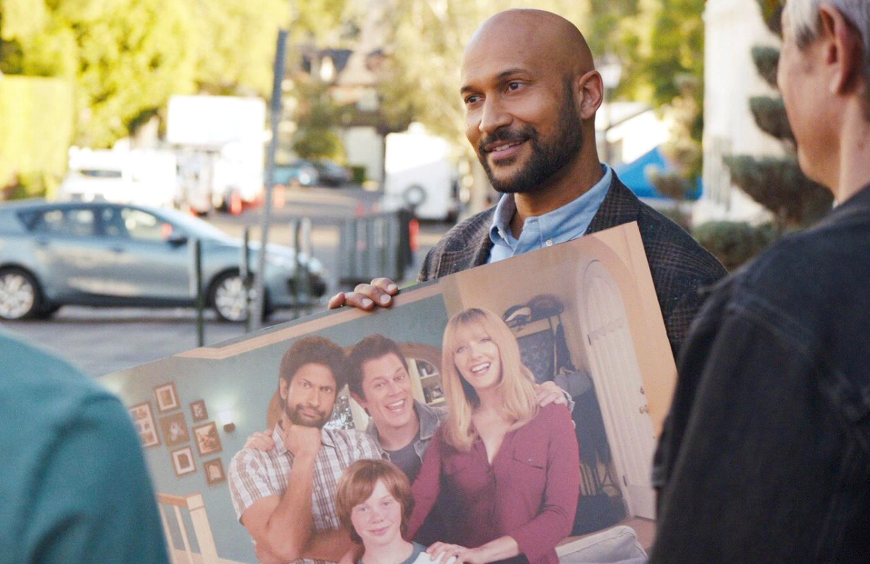 Then and Now: Reed (Keegan-Michael Key) holds a "vintage" cast photo from <i>Step Right Up</i>, the fictional '90s era sitcom at the heart of <i>Reboot</i>. (Photo: Hulu)