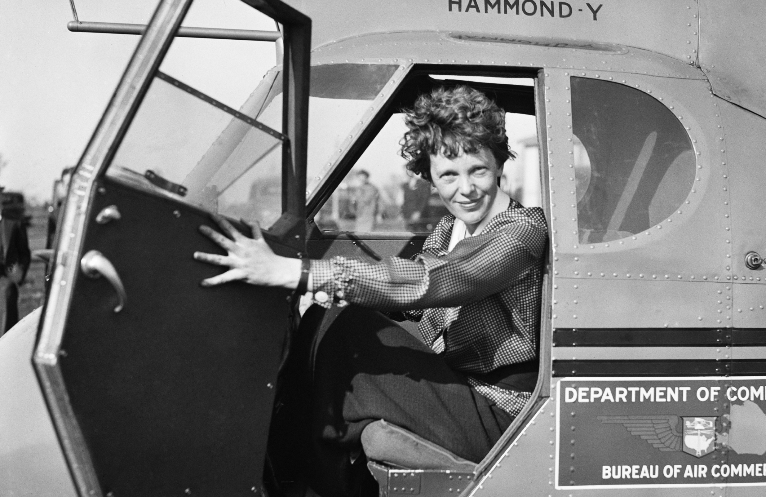 Amelia Earhart poses for a photo inside a plane (Image via Everett Collection)