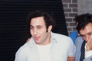 Police officers escort American accused (and ultimately convicted) serial killer David Berkowitz (left), known as the Son of Sam, into the 84th precinct station, New York, New York, August 10, 1977. (Image via Robert R. McElroy/Getty Images)